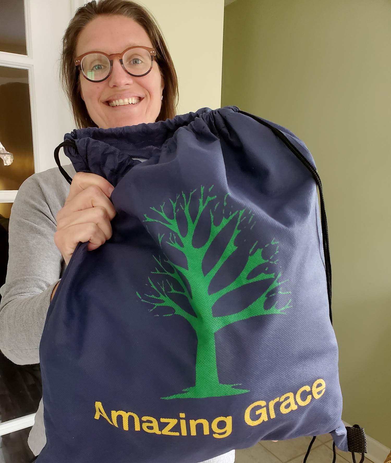 Woman holds bag with a tree and Amazing Grace printed on the outside