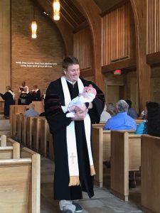Pastor Jonathan holding a baby in the sanctuary