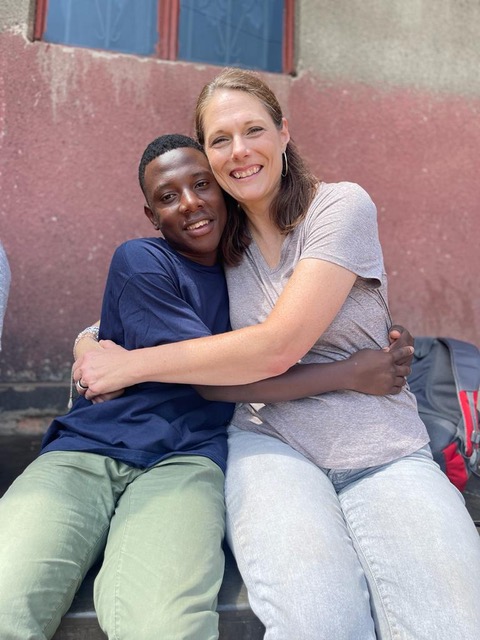 Photo of white woman and young black man posing with a smile and embrace..
