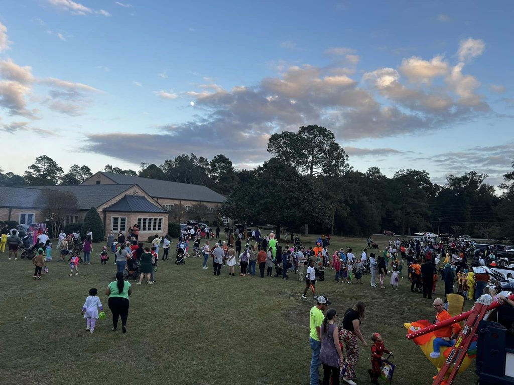 photo of Pittman Park's front lawn at dusk with dozens of people walking around.
