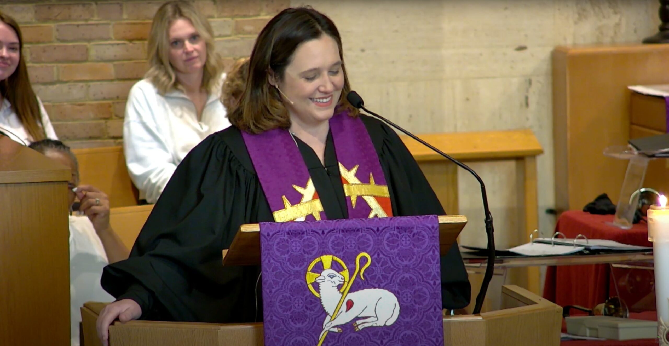 Pastor Stephanie at the pulpit, smiling