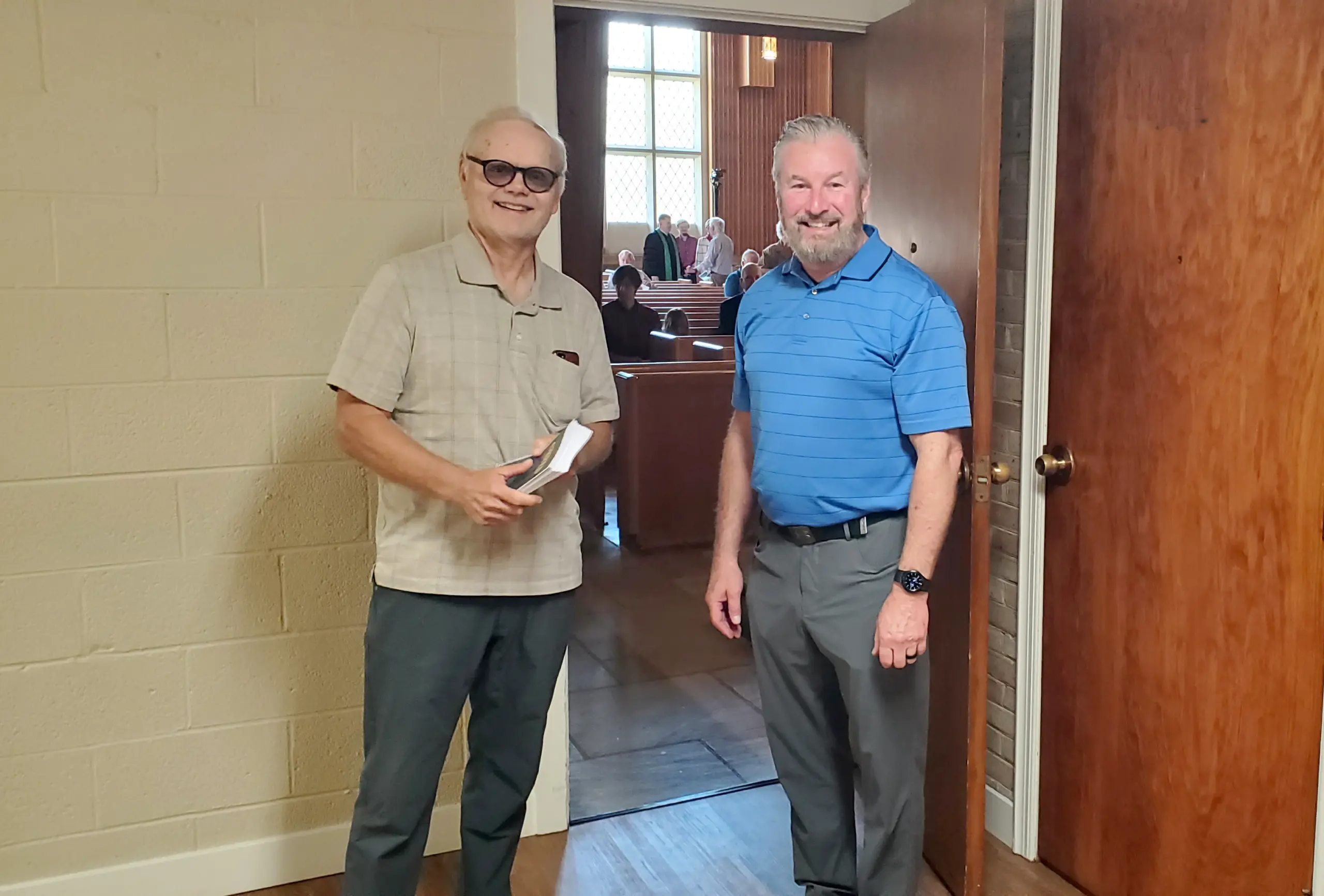 Photo of two men standing outside the sanctuary and looking at the camera