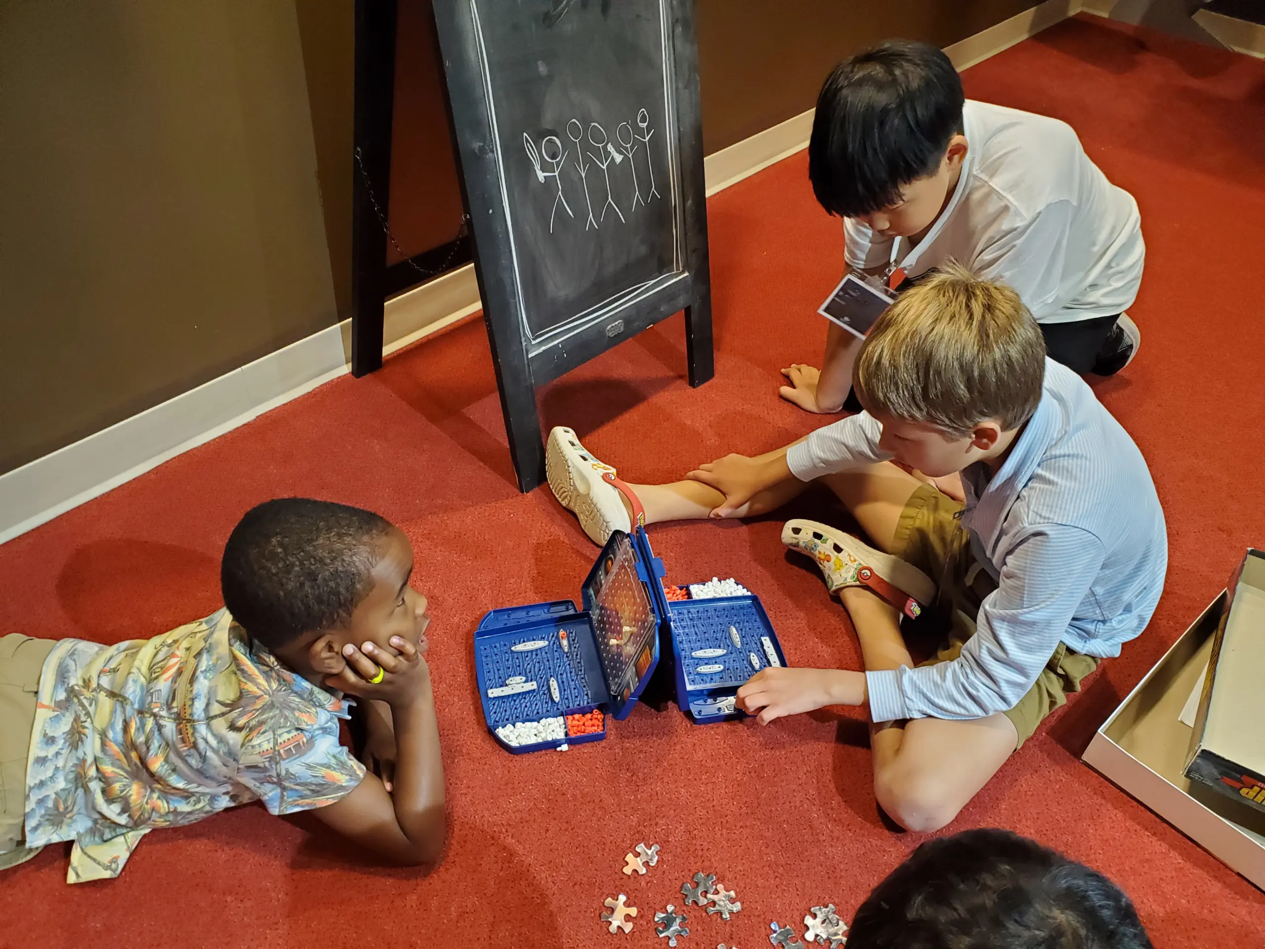 Photo from above of three boys playing Battleship