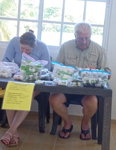 man and woman busy behind a table full of medication bottles