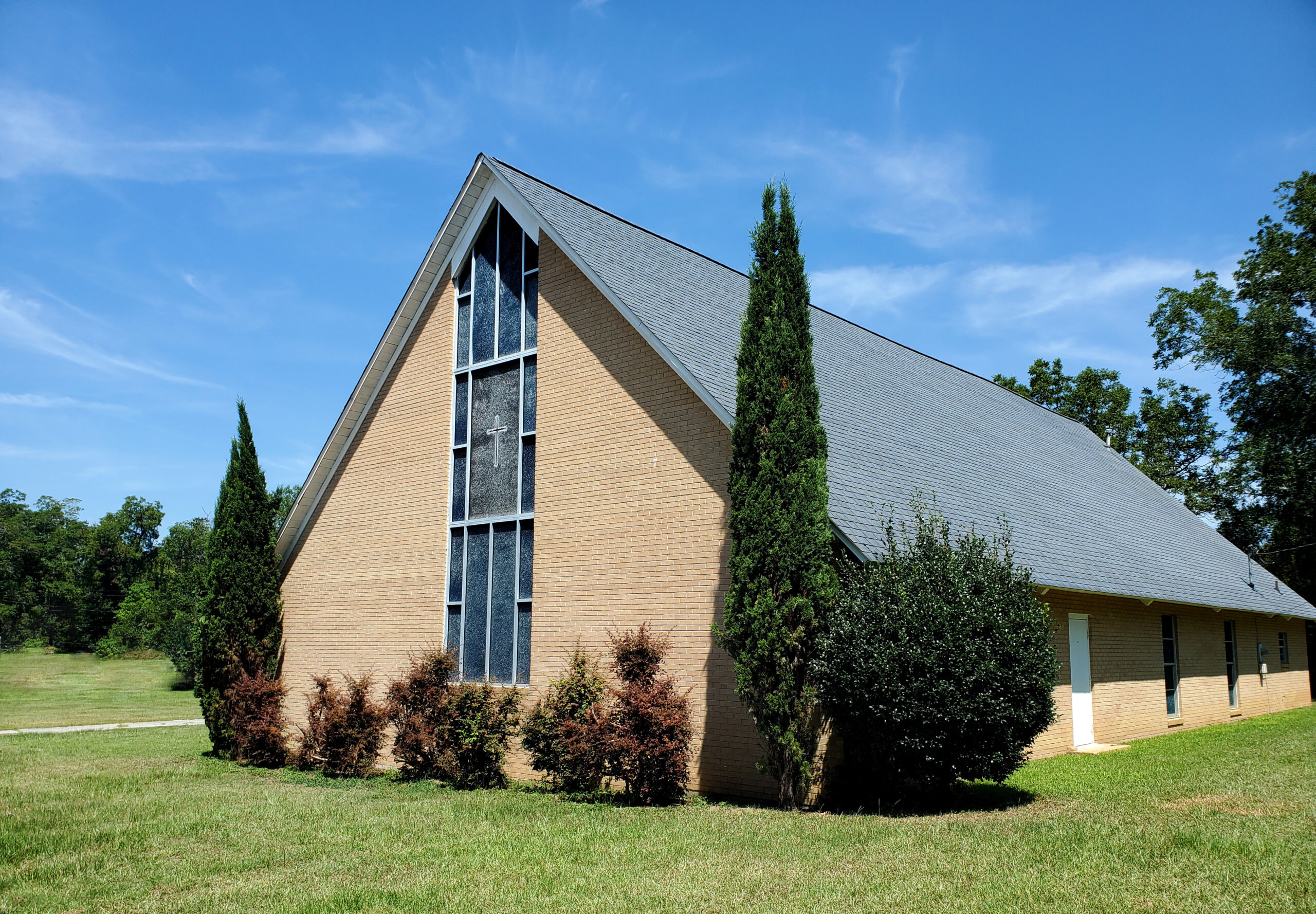 Stone building with high peak and windows inlaid with a cross