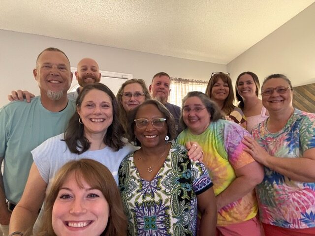 selfie of a group of 11 people in a living room